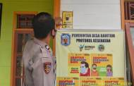 Briptu Tri Oktapianor Pasang Spanduk Prokes di Desa Binaannya